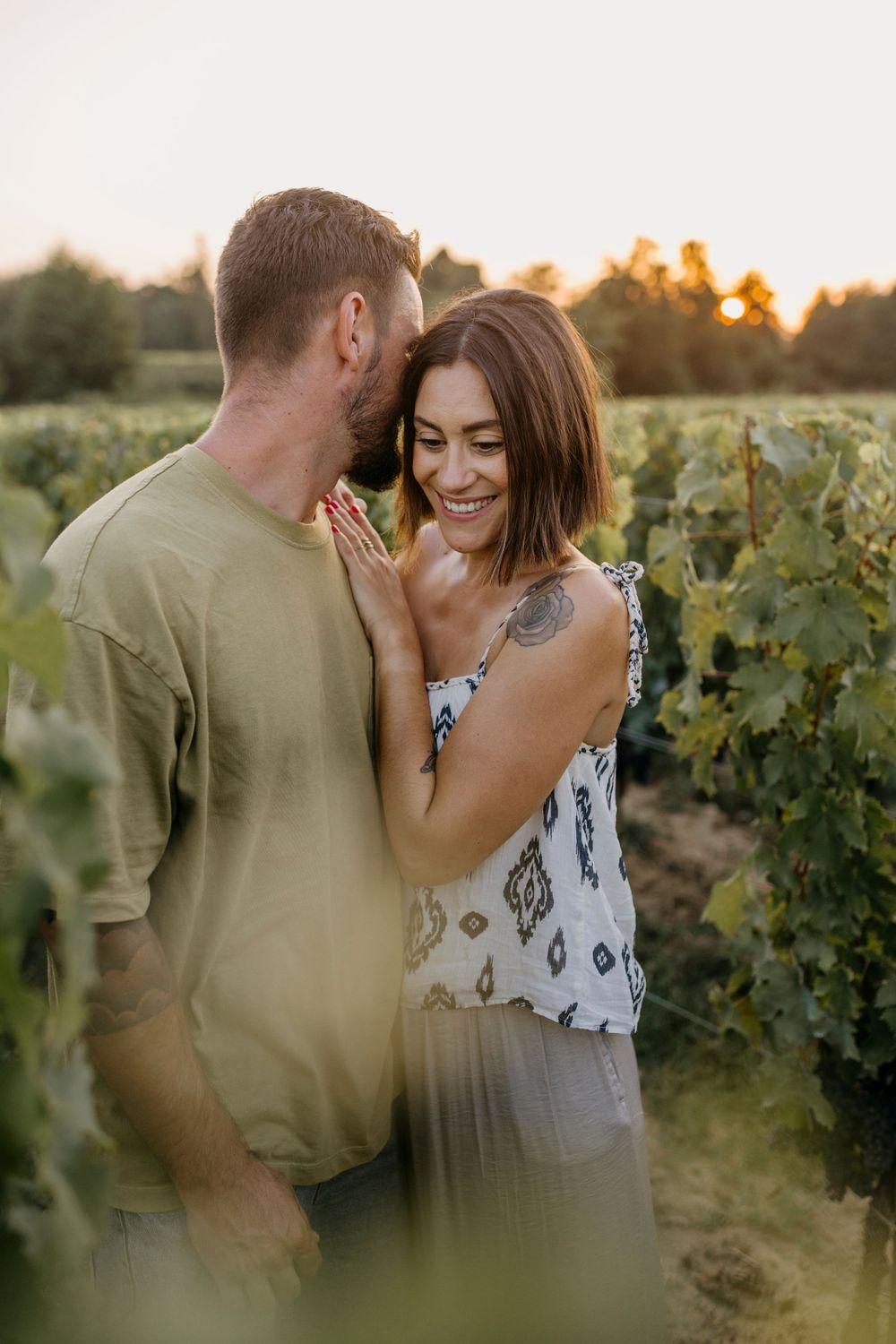 Couple laughing together in vineyard during golden hour sunset.