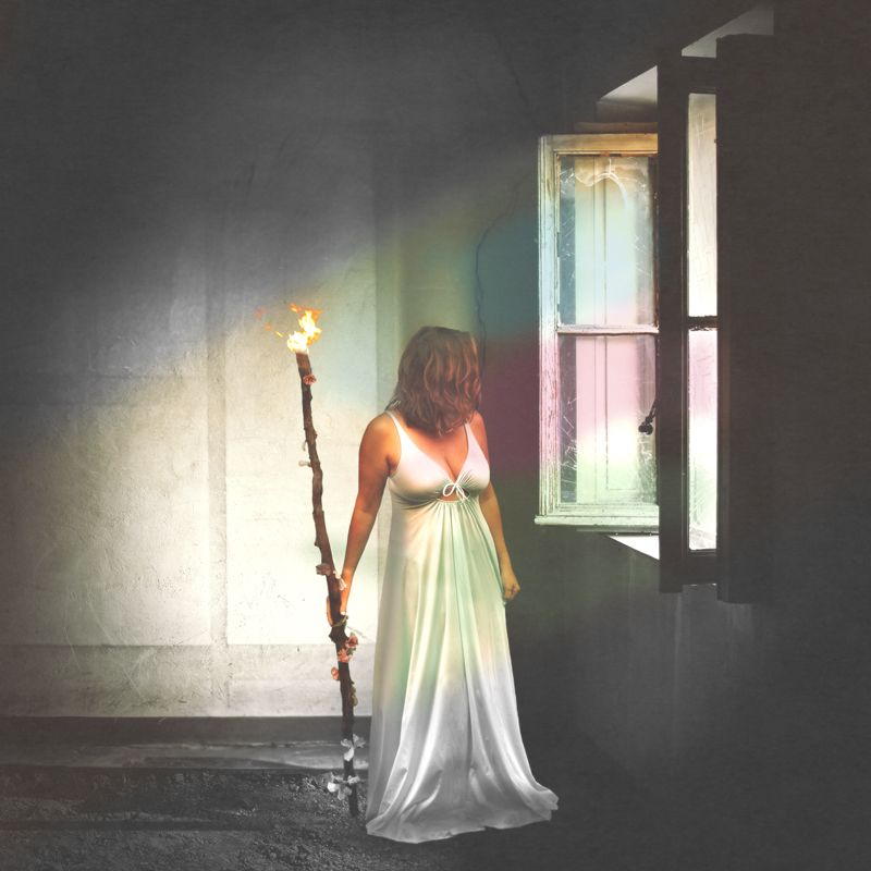 Ethereal white dress illuminated in dark room with dramatic window lighting.