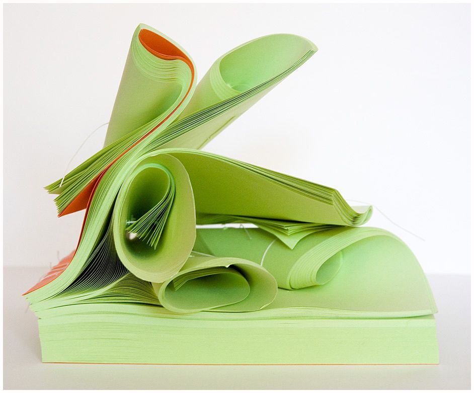 Series of green paper folding and bending patterns on white background showing origami techniques.