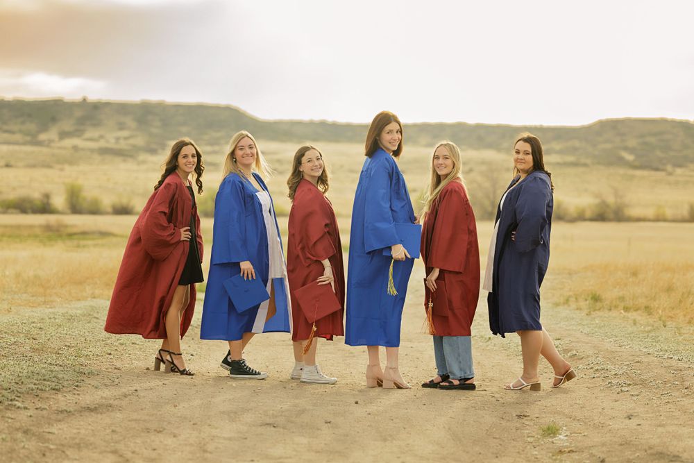Group portrait in vibrant red and blue coats standing together in a field at sunset.