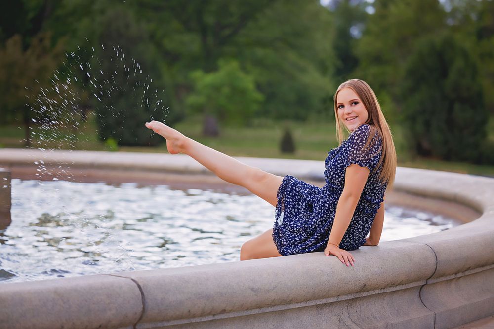 Playful scene of someone in a navy dress splashing water from a fountain.