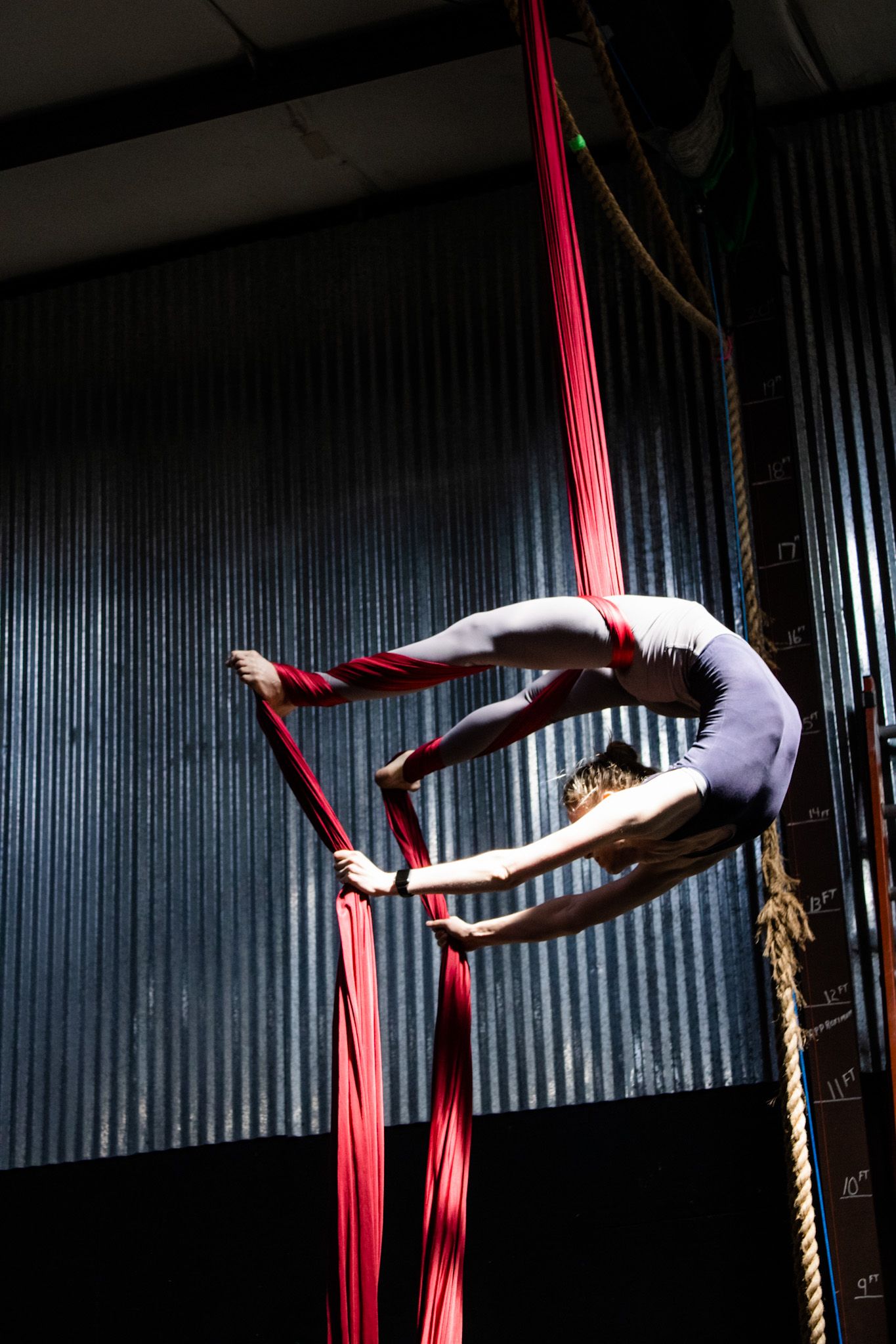 Woman on aerial silks doing a scorpion