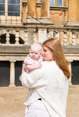 A tender moment captured outside a historic stone building on a sunny day.