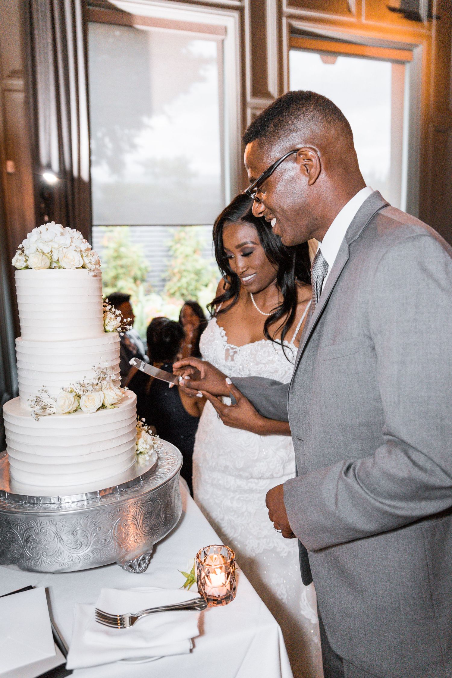 bride in white dress and groom in tux cutting 3 tier wedding cake together