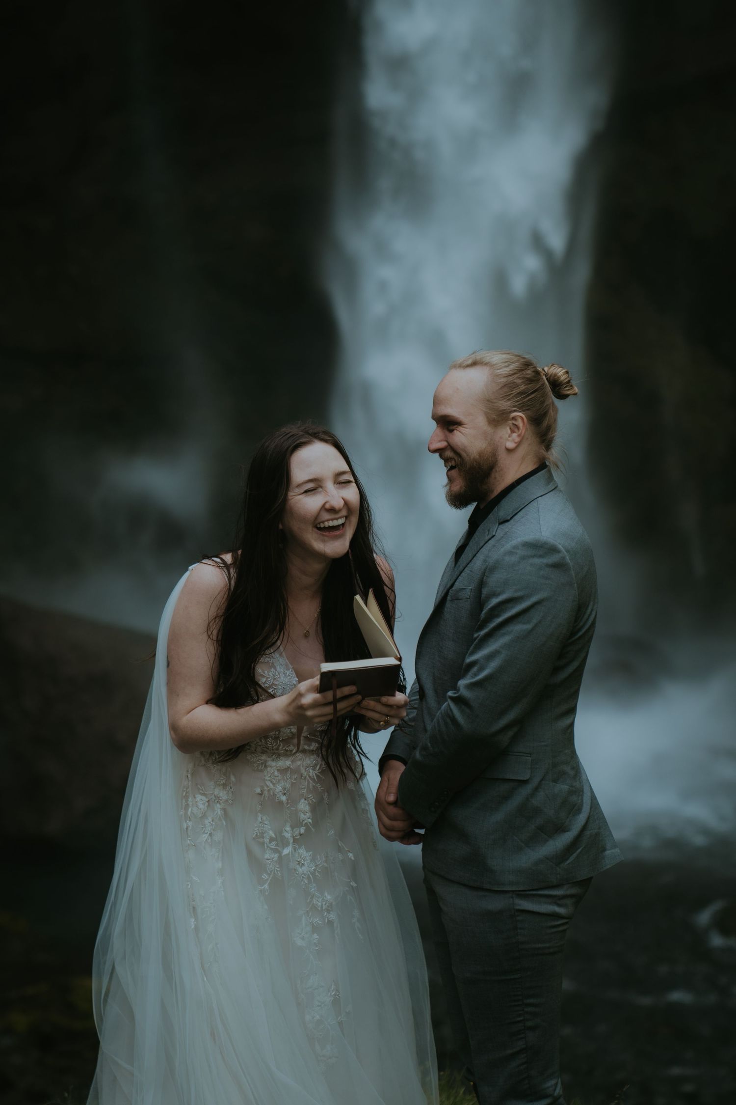 A joyful wedding moment shared beside a misty waterfall.
