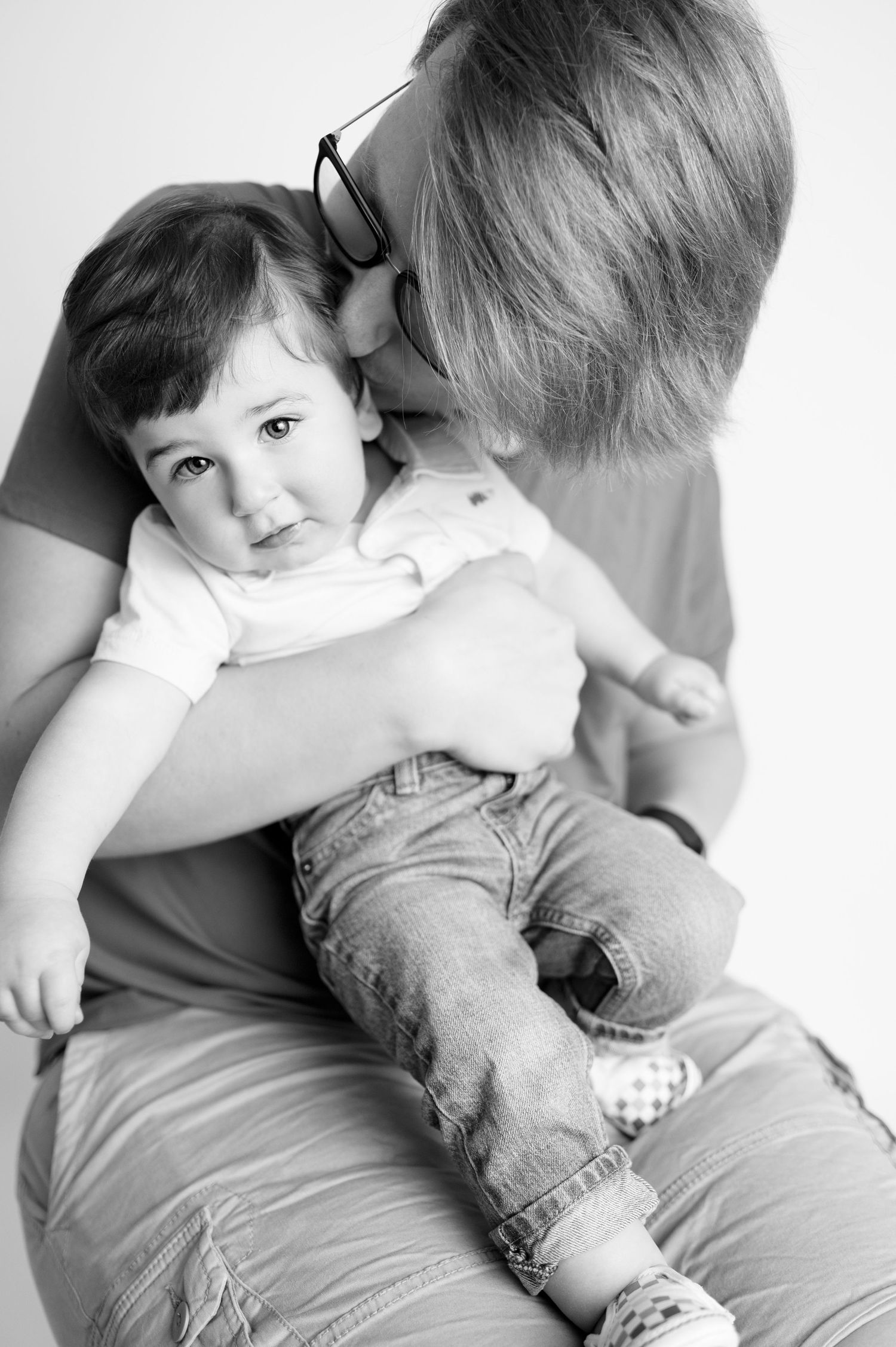 Black and white portrait of tender family moment against white backdrop.