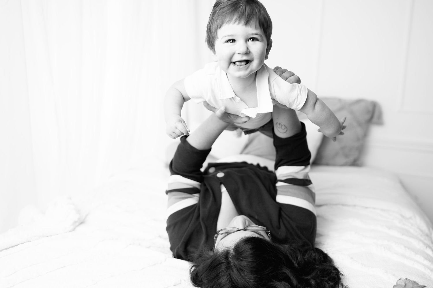 Child in black shows playful expressions during studio photoshoot against white background.