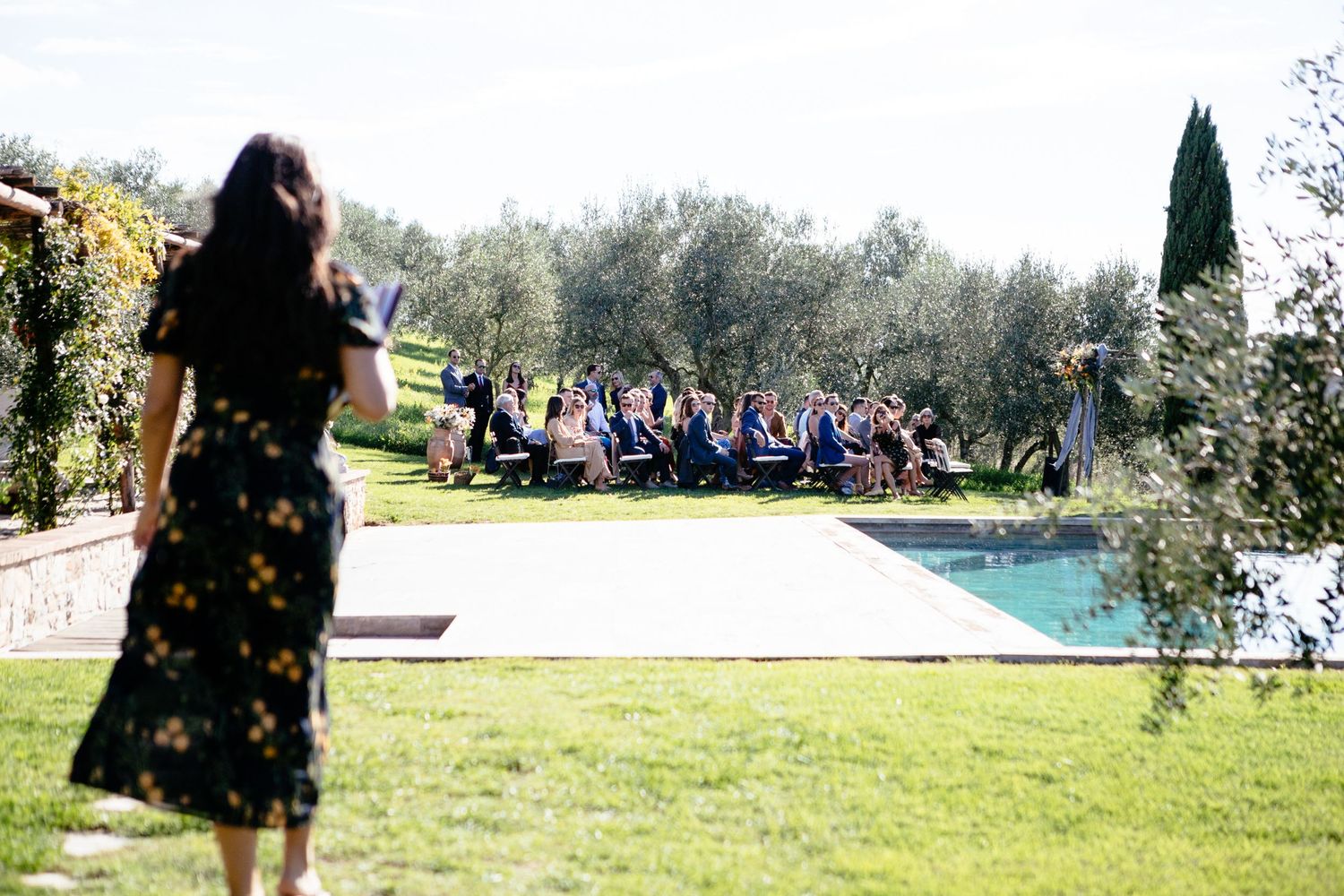 The celebrant leading this wedding at the Lazy Olive Tuscany walks towards where the ceremony is taking place outside.