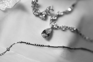 Close-up black and white photo of a delicate silver necklace with crystal pendant on soft fabric in the Hudson Valley,NY.