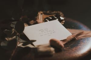 Handwritten note or letter photographed in dramatic lighting with decorative elements.