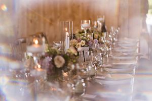 Elegant wedding reception table setting with floral centerpieces and crystal glassware.