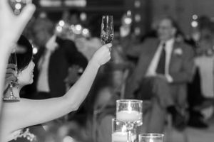 Black and white image of champagne glass raised in celebration at wedding reception in the Hudson Valley,NY.