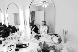 Black and white photo showing a bridal preparation scene with mirrors and makeup supplies.