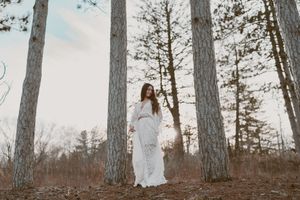 A ethereal bridal portrait among tall pine trees with sunlight filtering through the branches.
