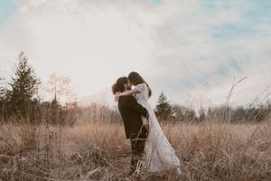 A romantic embrace in a misty field with winter trees in the background.