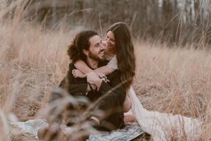 An intimate moment captured between a couple in a rustic field during golden hour.