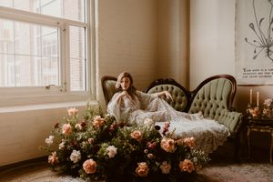 A dreamy boudoir scene with vintage furniture surrounded by pink roses and natural window light.