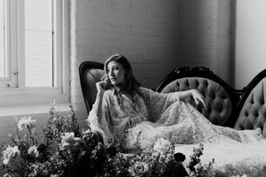 A classic black and white portrait on an antique chaise lounge surrounded by flowers.