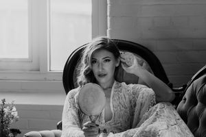 Classic black and white portrait showing elegant pose on vintage furniture.