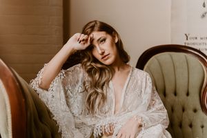 Ethereal boudoir portrait featuring delicate lace robe and antique furniture.