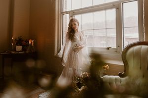 Dreamy window light illuminates figure in lace against vintage decor.