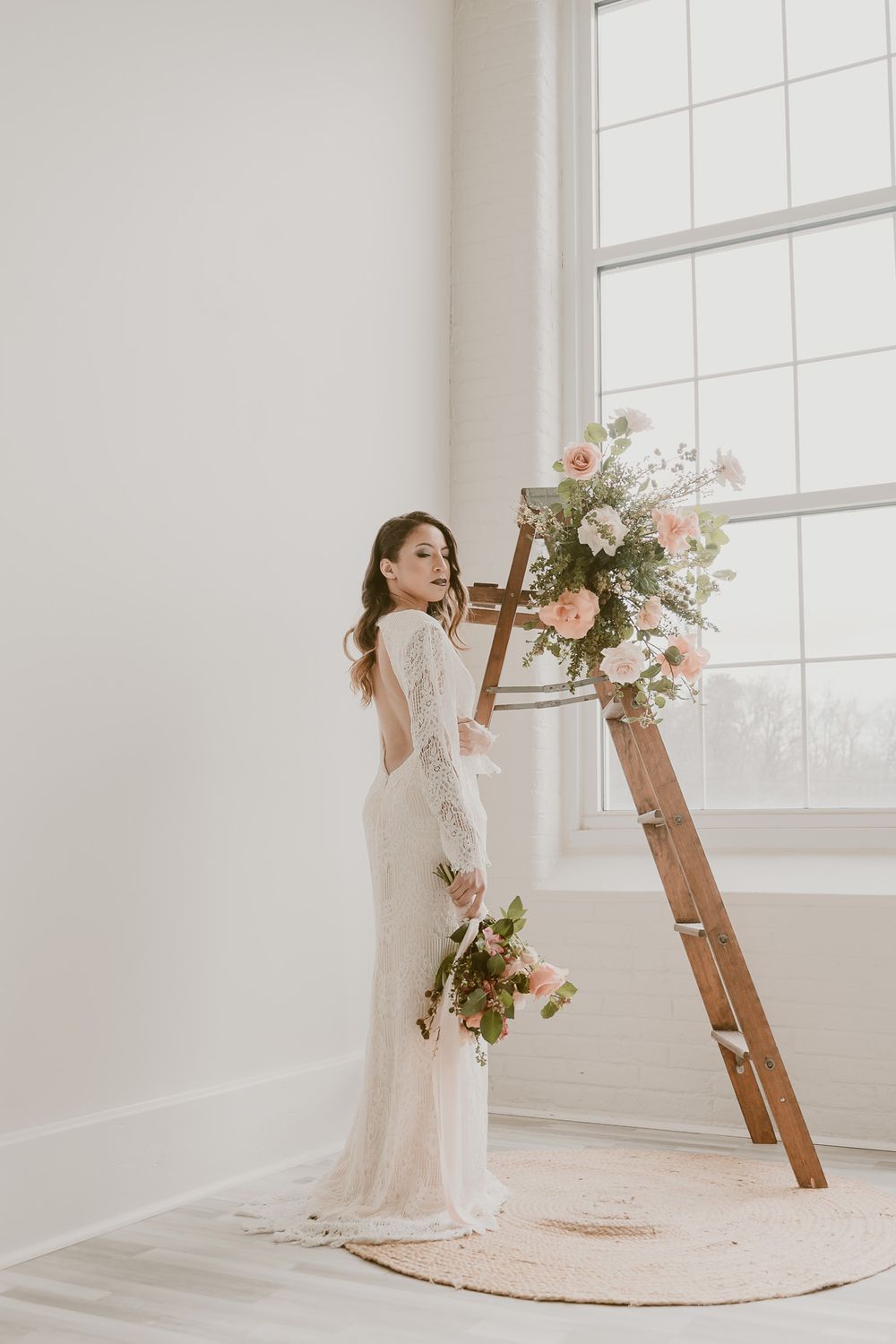 Elegant bridal pose with wooden ladder decorated in fresh pink and white flowers.