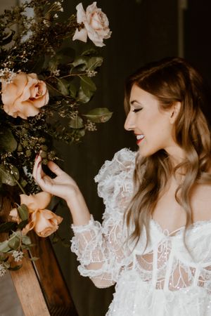 A close-up shot of a bride admiring pink roses on a wooden ladder display.