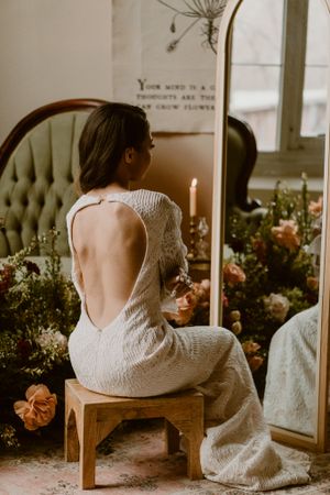 Romantic backless wedding dress photographed in candlelight with floral decorations and vintage mirror in the Hudson Valley,NY.