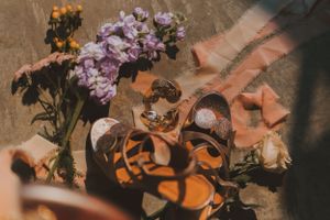 Close-up of orange butterflies and purple flowers arranged on a textured surface.