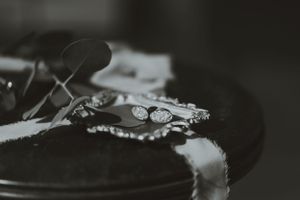 Close-up black and white shot of wedding rings on dark fabric.