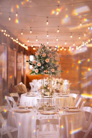 Wedding reception venue with string lights and tall floral centerpieces on white-clothed tables in the Hudson Valley,NY.