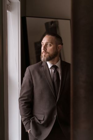 Classic formal attire with black suit photographed in moody window light.