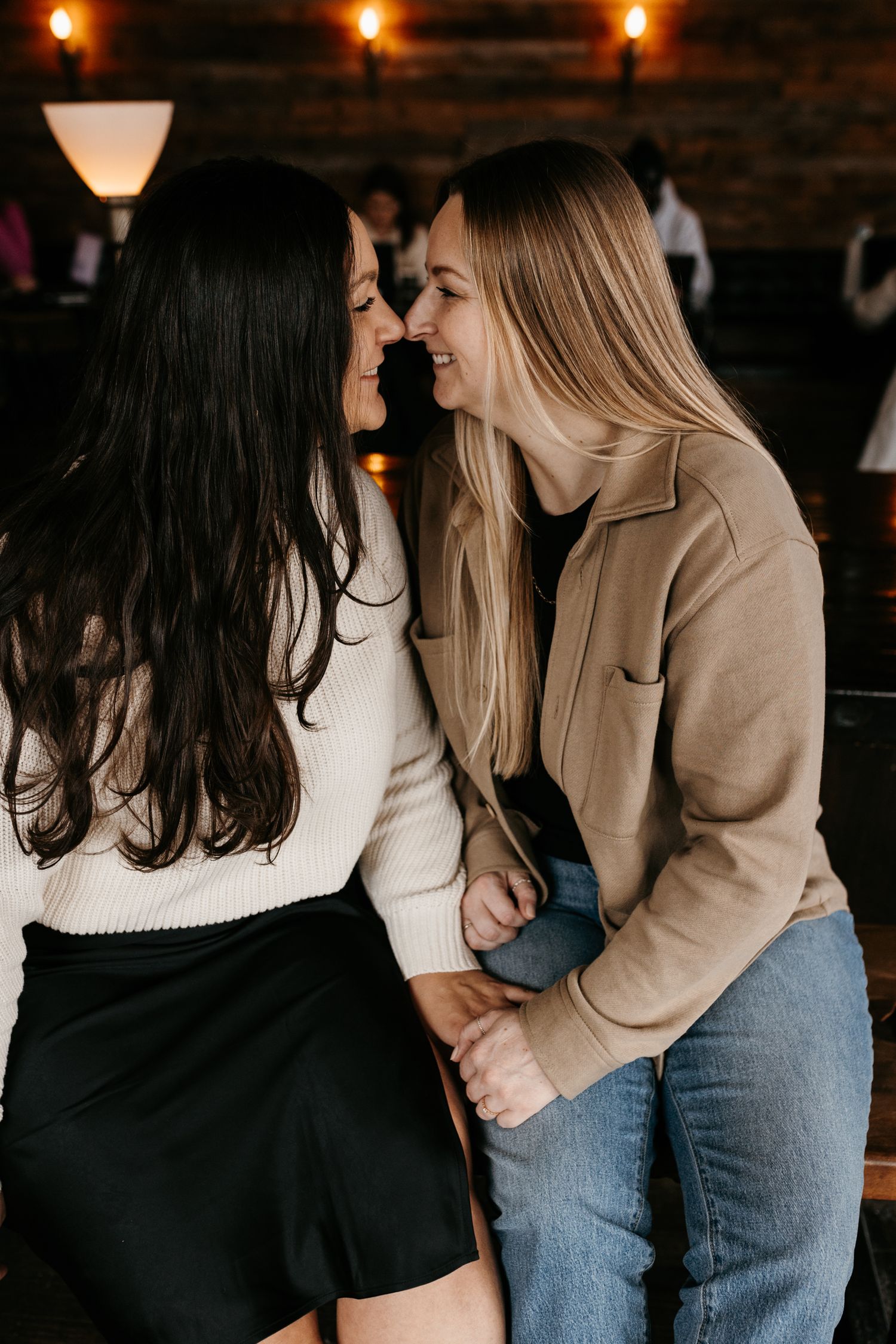 Two people sharing a close moment in a dimly lit restaurant with exposed brick walls.