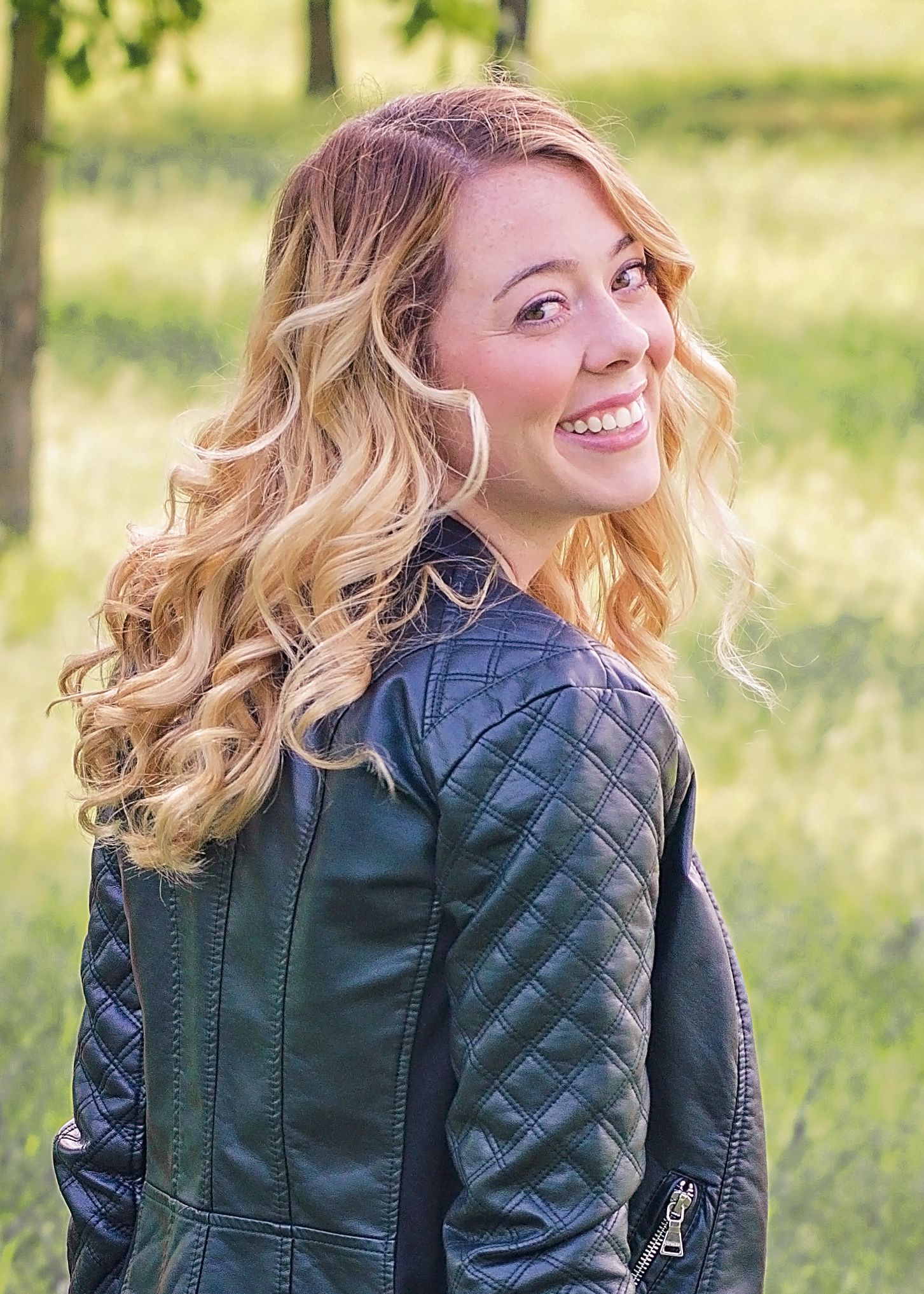 Young woman with curly hair and leather coat looking over shoulder