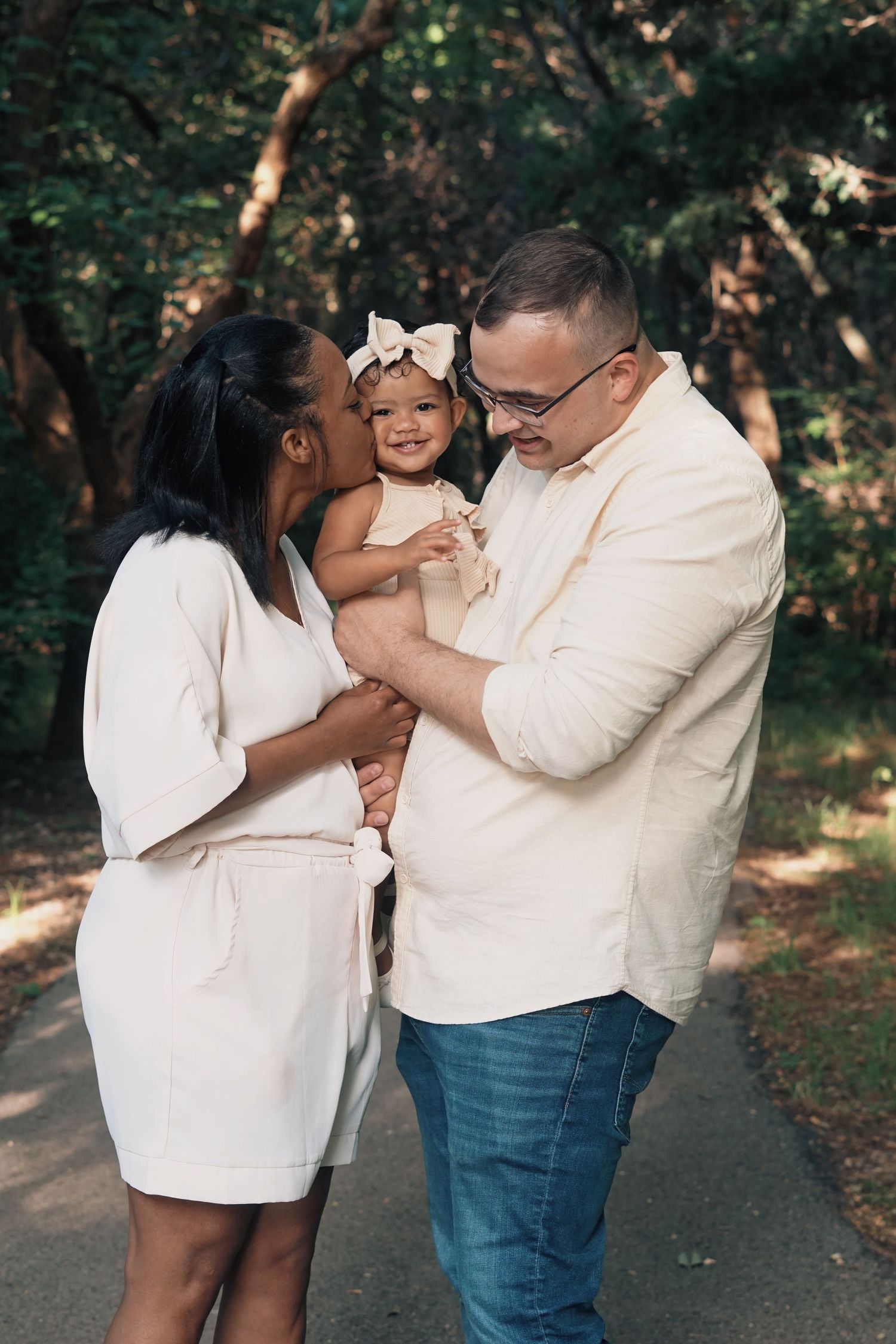 A family shares a joyful moment together outdoors, wearing coordinated cream-colored outfits.