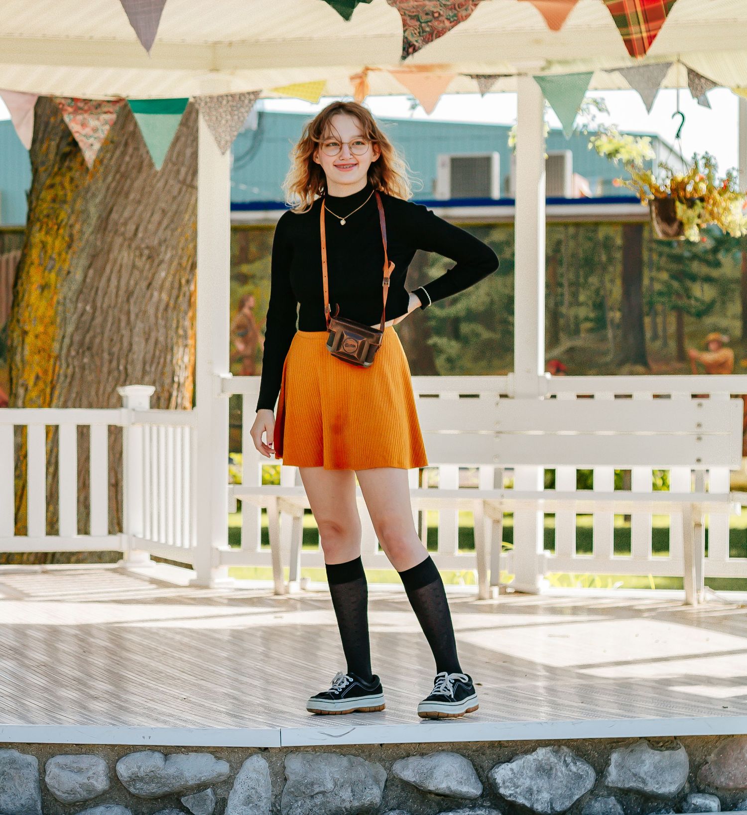 Colorful bunting decorates a gazebo while orange skirt and knee socks create retro fashion look.