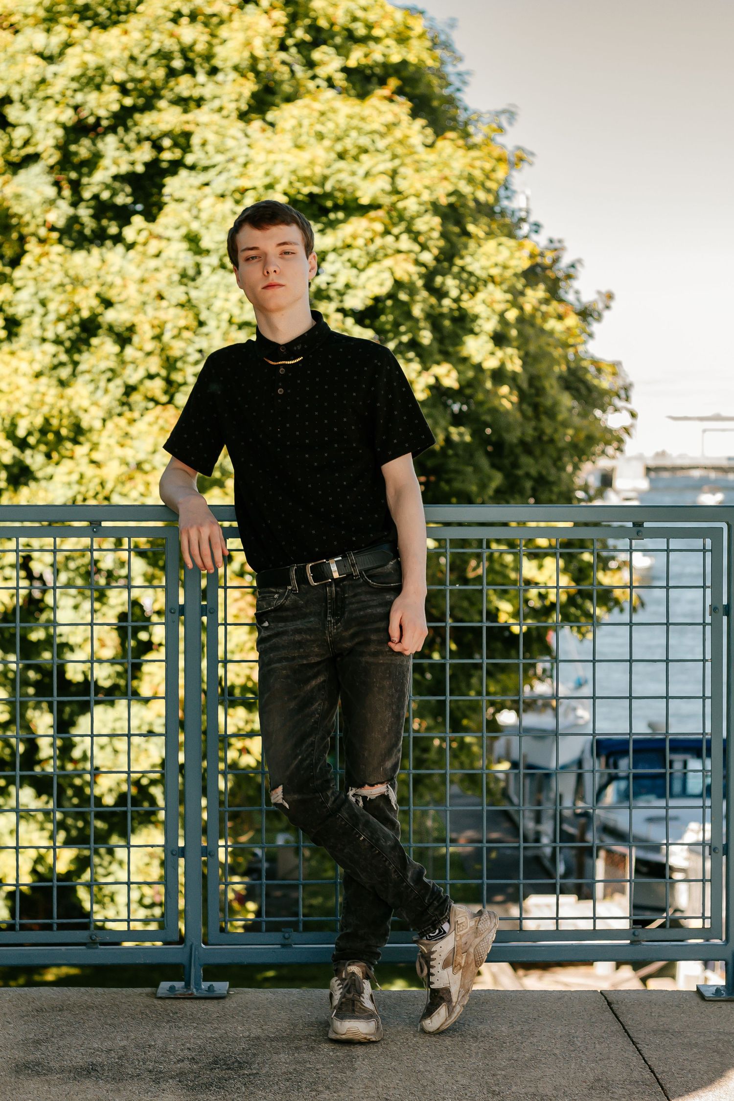 All-black casual outfit contrasts with blooming yellow flowers in urban setting.