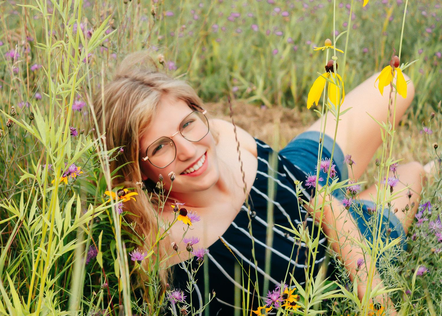 Casual lifestyle portrait lying in summer wildflower field with yellow blooms.
