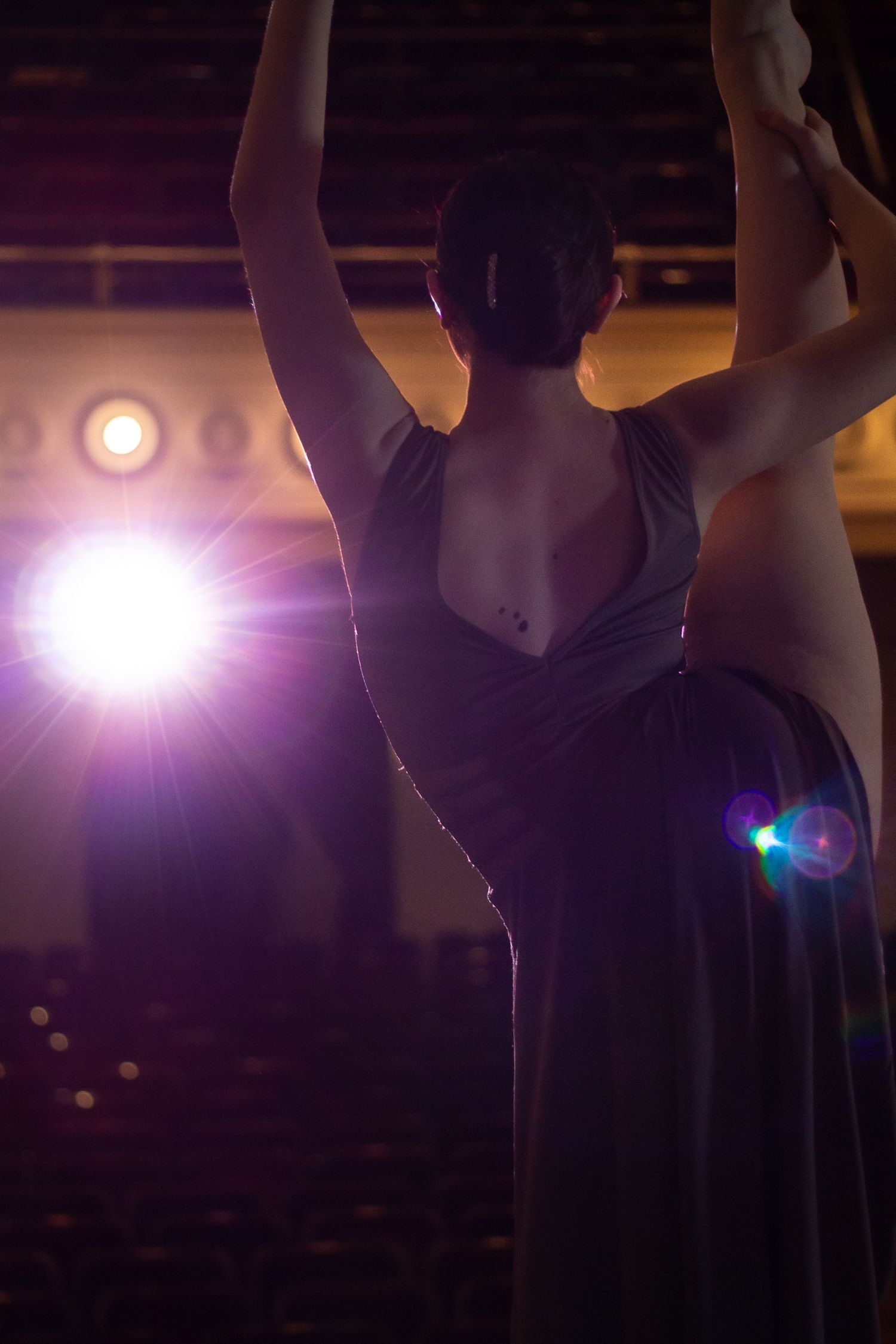 A silhouetted dancer strikes a dramatic pose on stage with theatrical lighting.