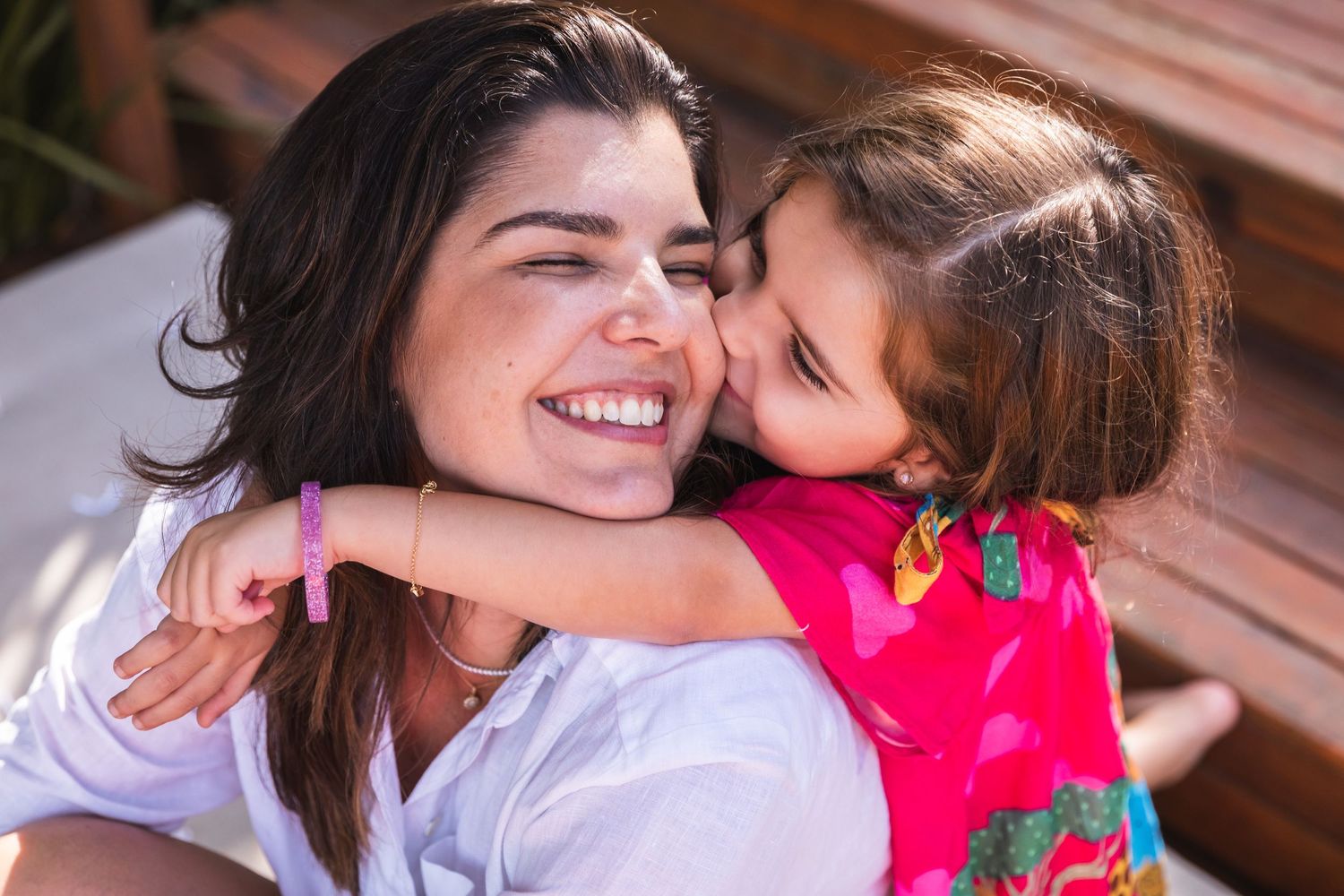 A sun-lit candid moment of affection between two people sharing joyful smiles.