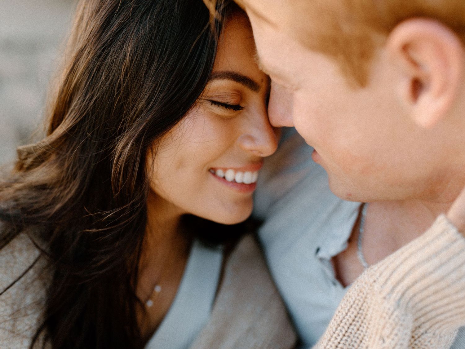 A couples photoshoot by Moments With Kell on Oahu in Hawaii with husband and wife cuddling on the beach