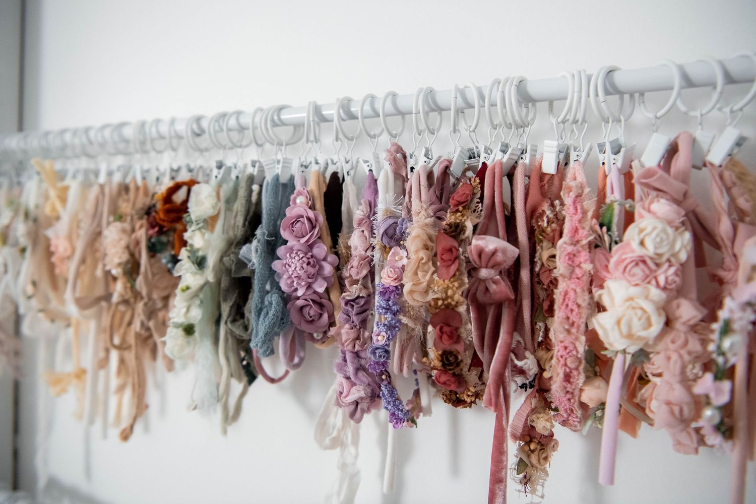 Romantic collection of lace and floral dresses hanging on white clothing rack.