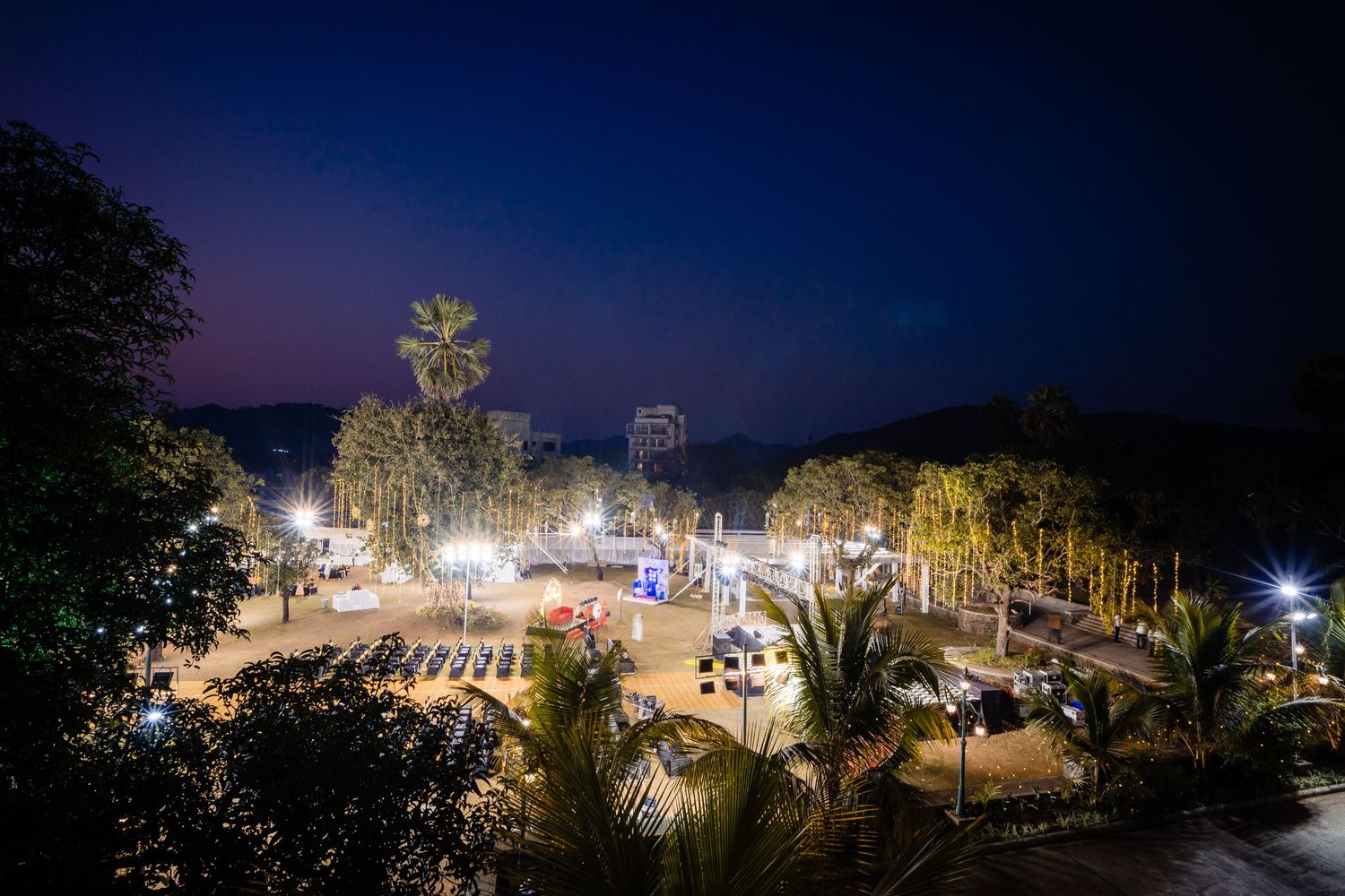 Panoramic nighttime view of an outdoor wedding venue with twinkling lights and palm trees.