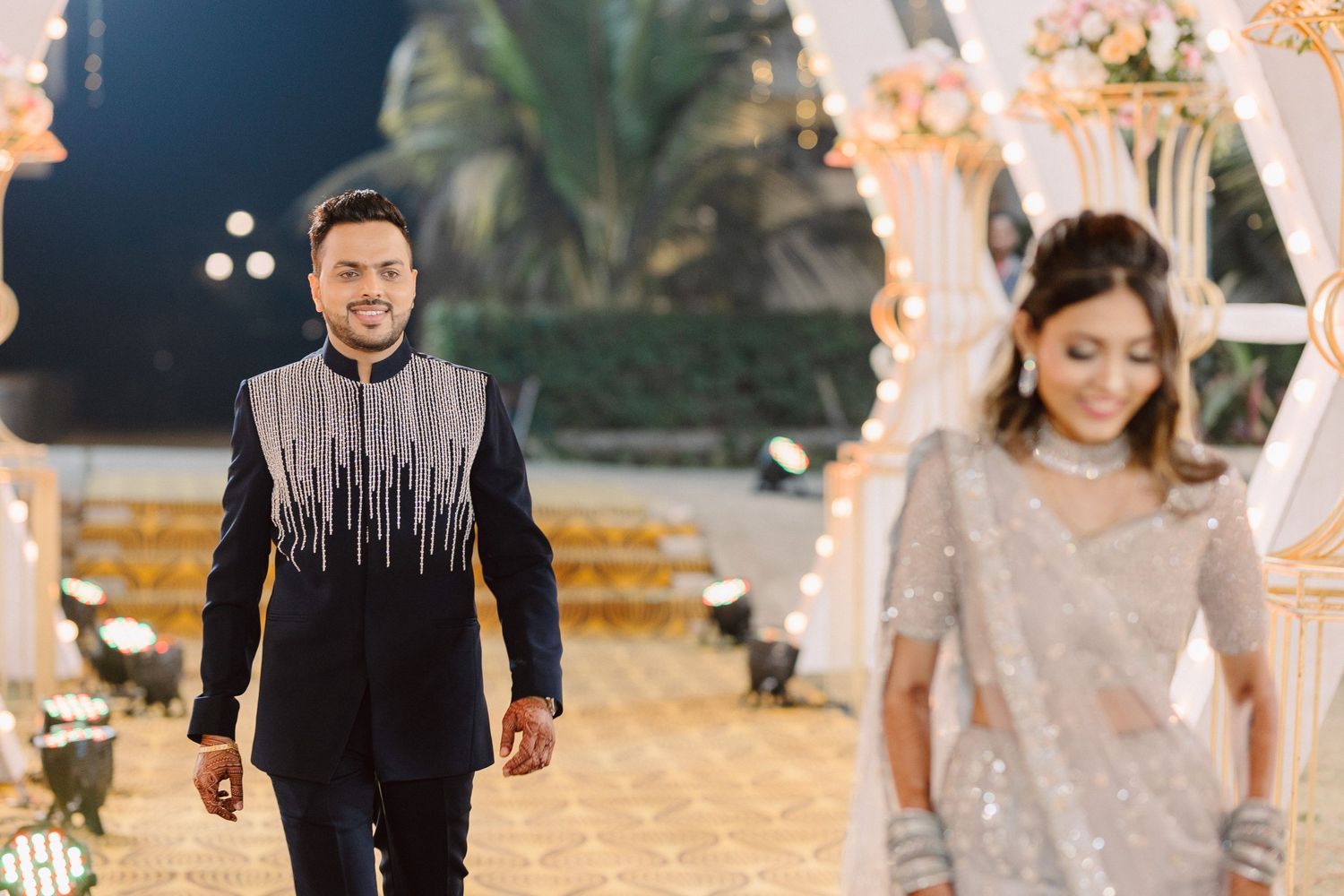 Festive outdoor wedding celebration with decorative lighting and palm trees in the background.