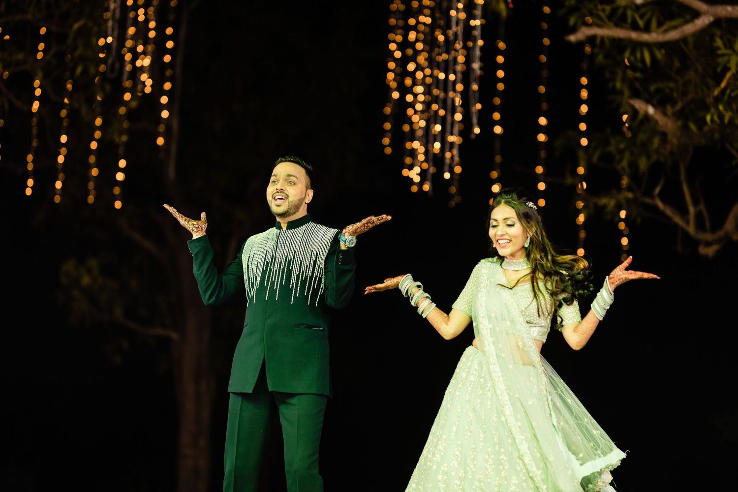 Dancers in elegant attire perform choreographed moves against a backdrop of twinkling lights.