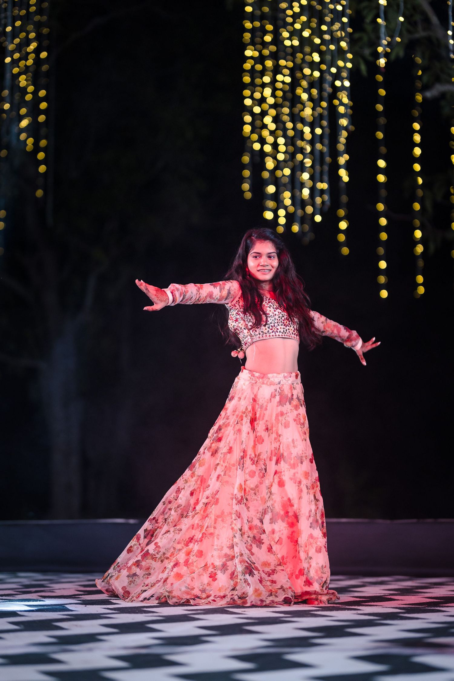Solo dancer in a flowing coral dress twirls gracefully on a checkered dance floor.