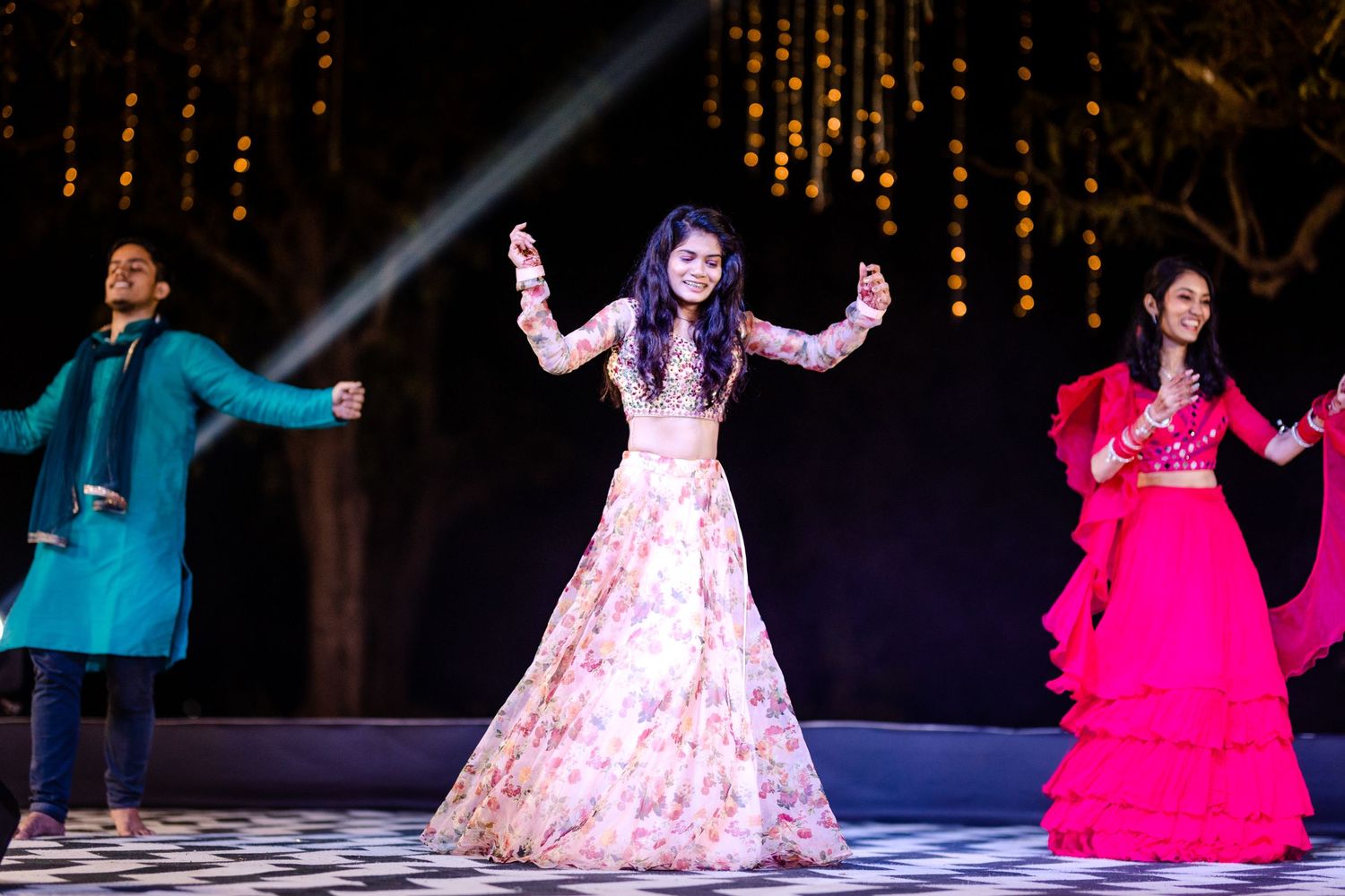 Dancers in colorful traditional outfits perform a synchronized routine under string lights.