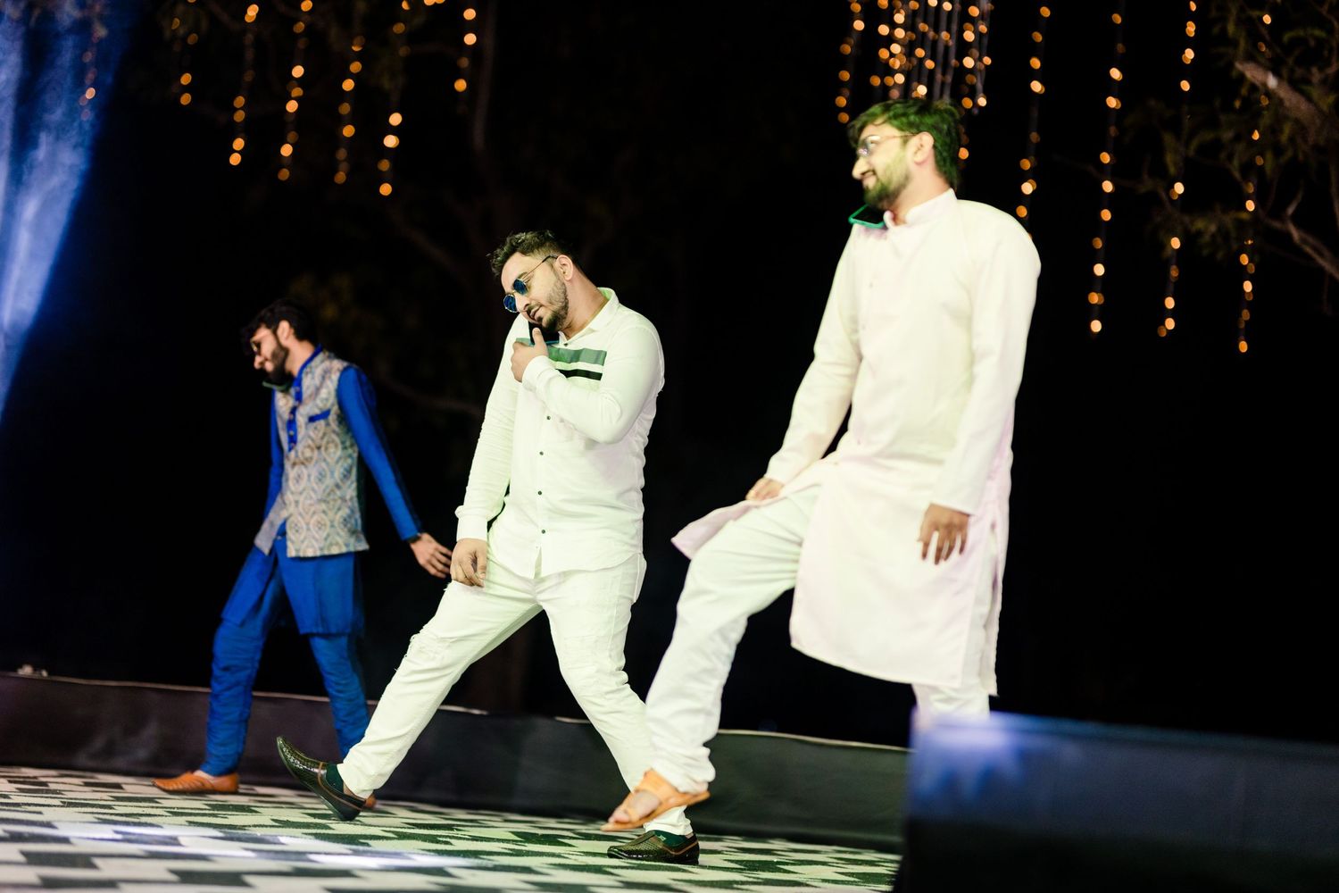Dancers in white outfits perform a synchronized routine on a dramatically lit stage.