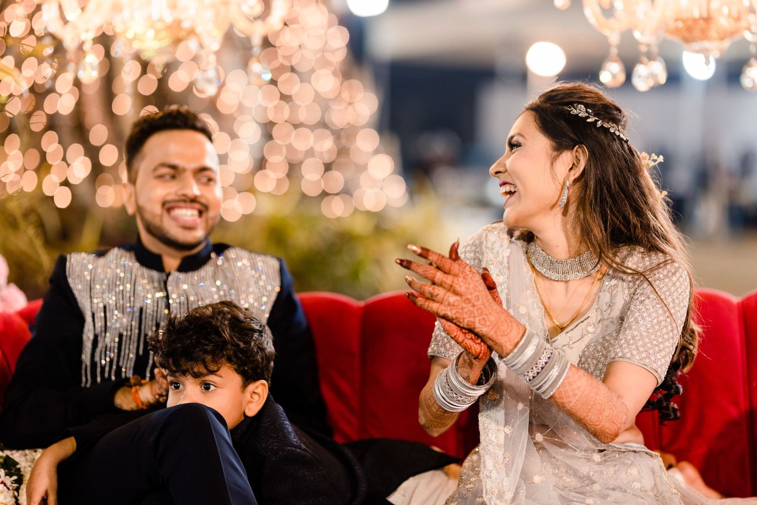 Guests celebrate at an elegant reception under sparkling chandeliers and warm lighting.