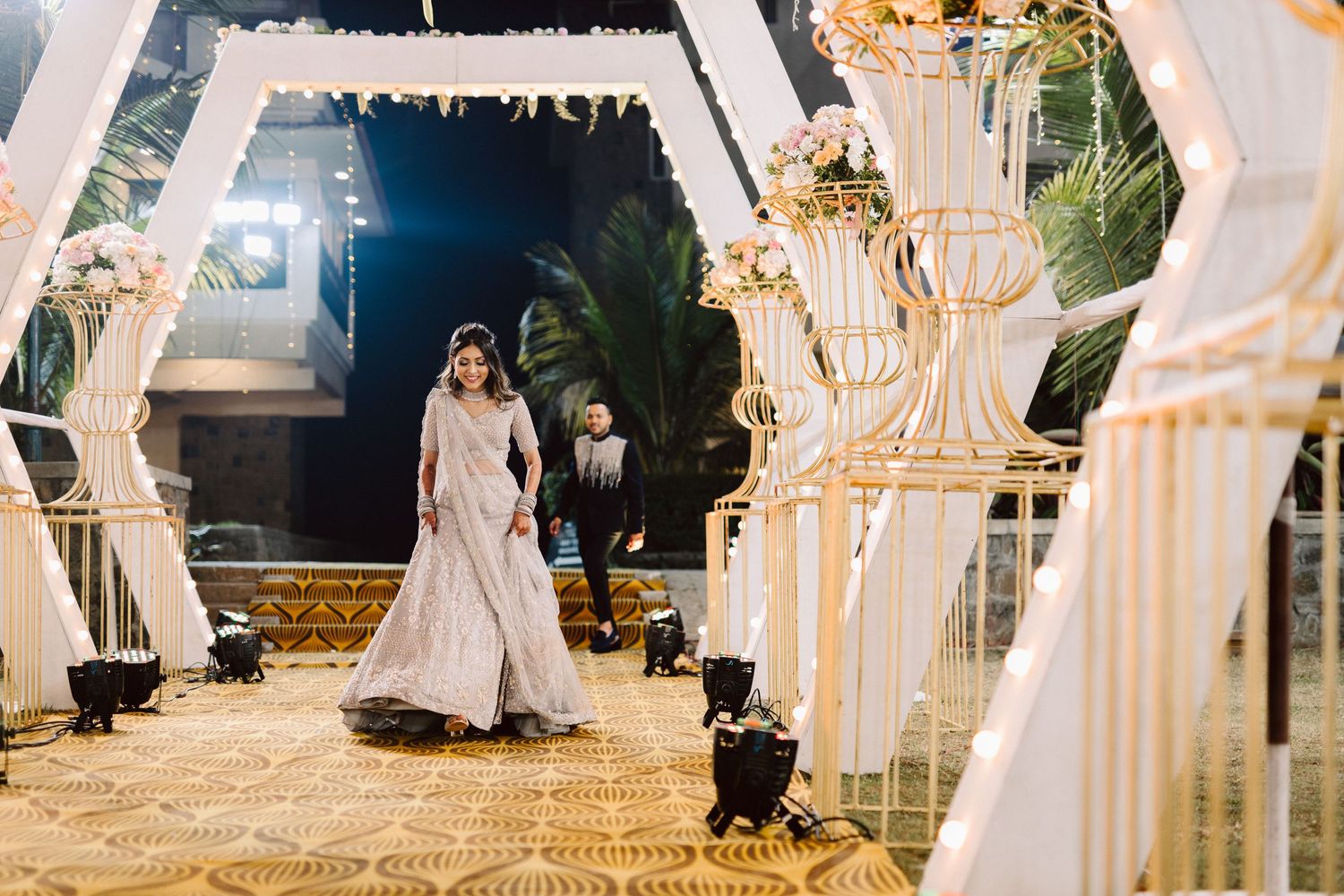 Elegant outdoor wedding venue with white chairs and decorative lighting at night.